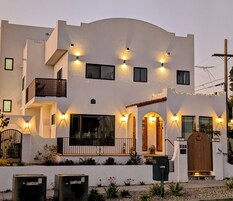 A two-story building with a balcony, multiple windows, and outdoor lighting.