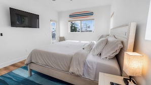 Une chambre à coucher avec un lit, un téléviseur fixé au mur, une fenêtre donnant sur un beau paysage et une lampe sur la table de chevet.