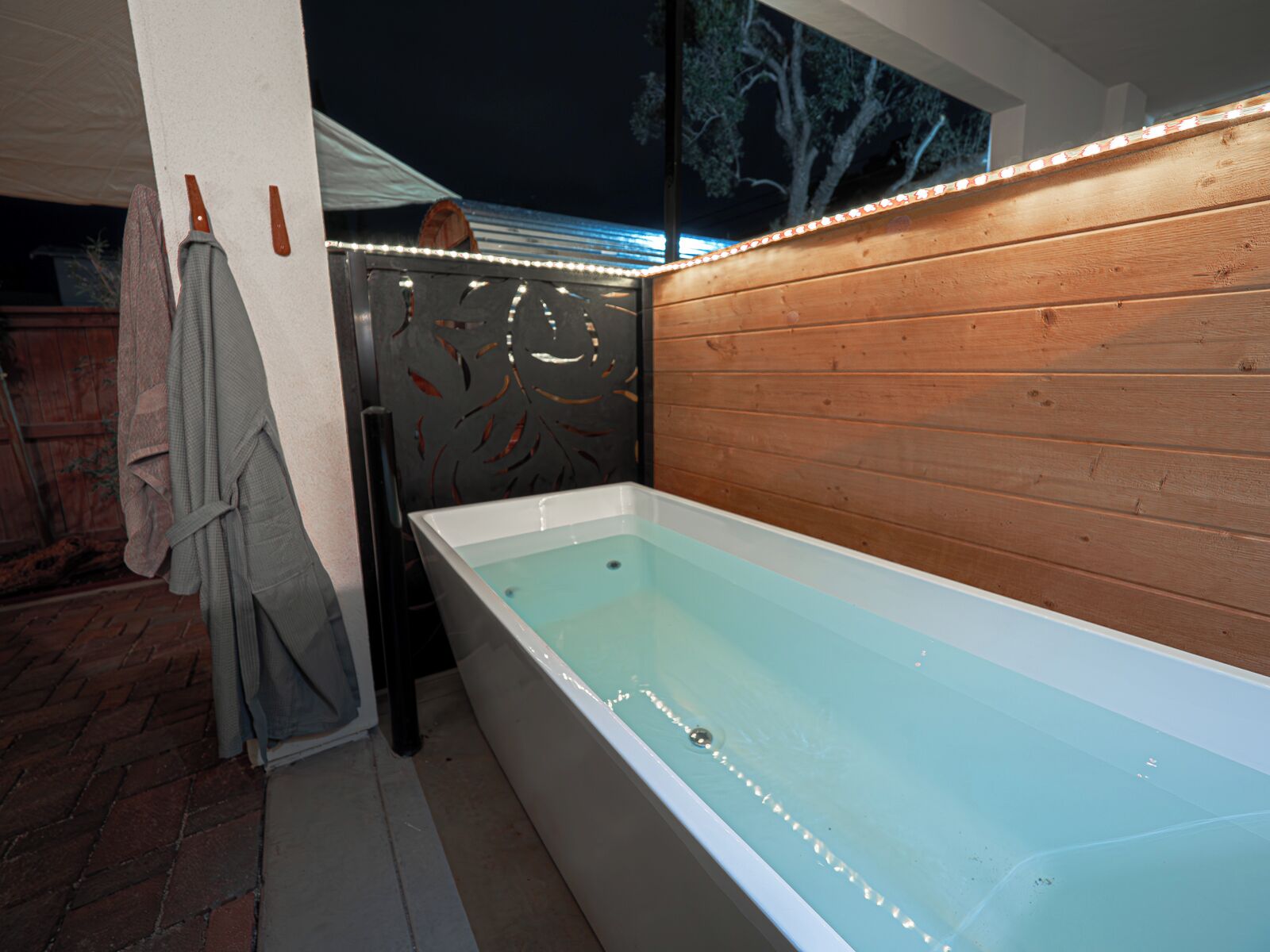 Un baño moderno con una bañera independiente, paneles de madera y un detalle decorativo en la pared.