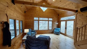 A cozy cabin with wooden walls, a sloped ceiling, and large windows offering views of a snowy landscape. - Tranquil Amish-built cabin near Wildcat State Park (Ontario)