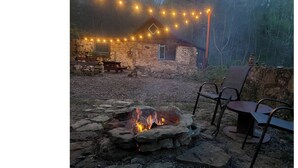 A rustic stone building with string lights, a stone fire pit, and outdoor seating. - Tranquil Amish-built cabin near Wildcat State Park (Ontario)