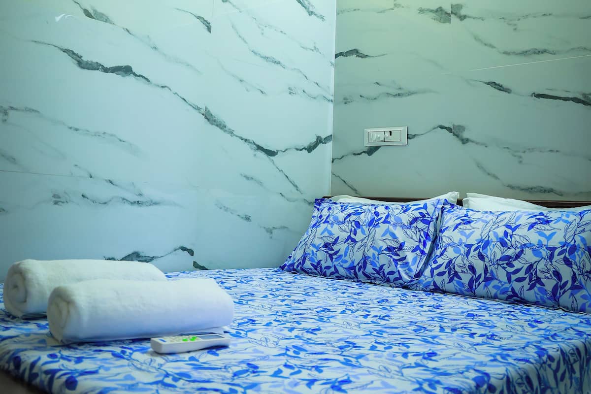 Une chambre avec un lit, un ventilateur de plafond et des murs décorés d’un motif imitant le marbre.