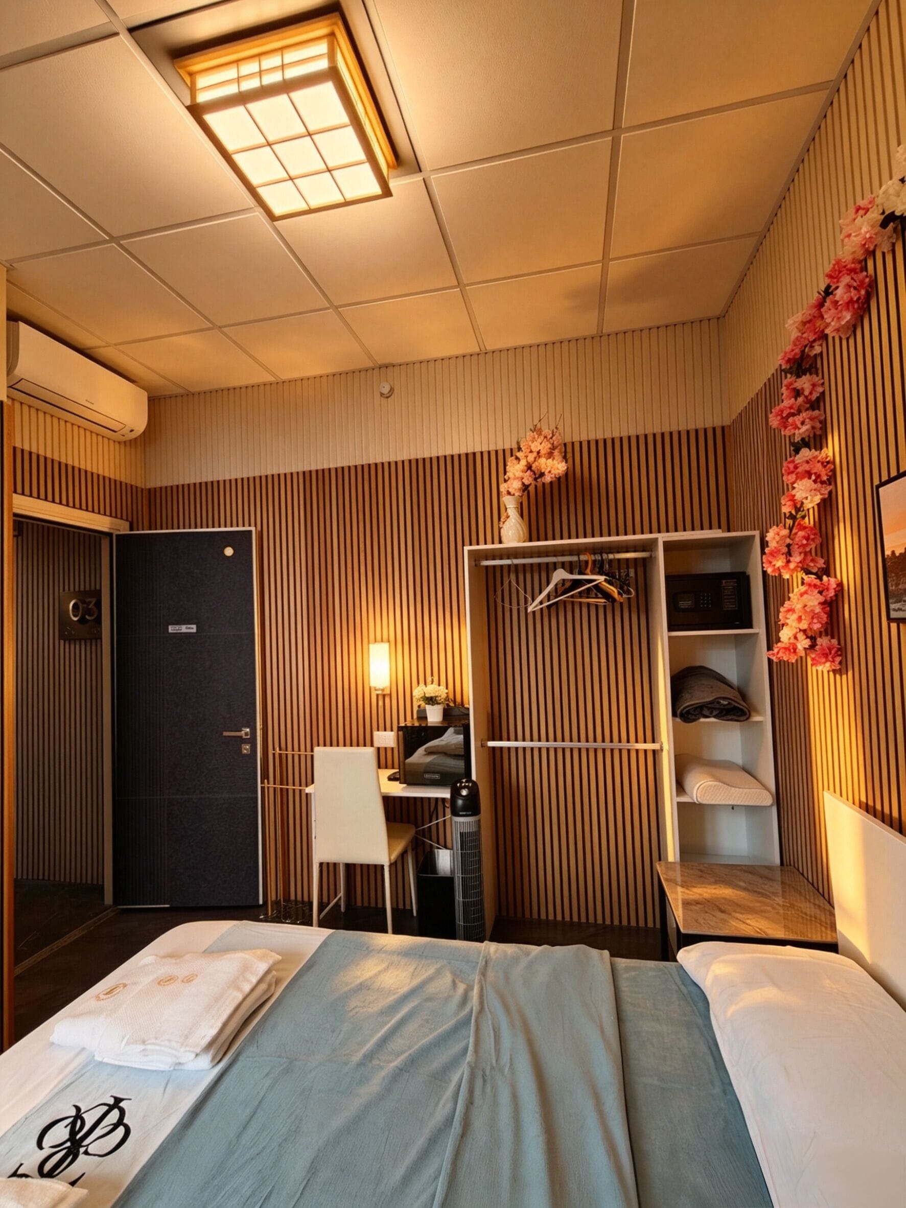 Une chambre d’hôtel comprenant un lit, un bureau, une armoire et une coiffeuse avec un miroir.