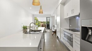 Una cocina moderna con una isla central, electrodomésticos de acero inoxidable e iluminación colgante.