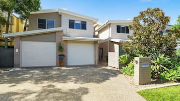 Un immeuble résidentiel à deux étages, doté d’un garage, d’une allée et d’une pelouse bien entretenue.