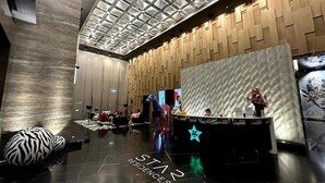 A modern lobby with a high ceiling, a reception desk, and a star-shaped light decoration.