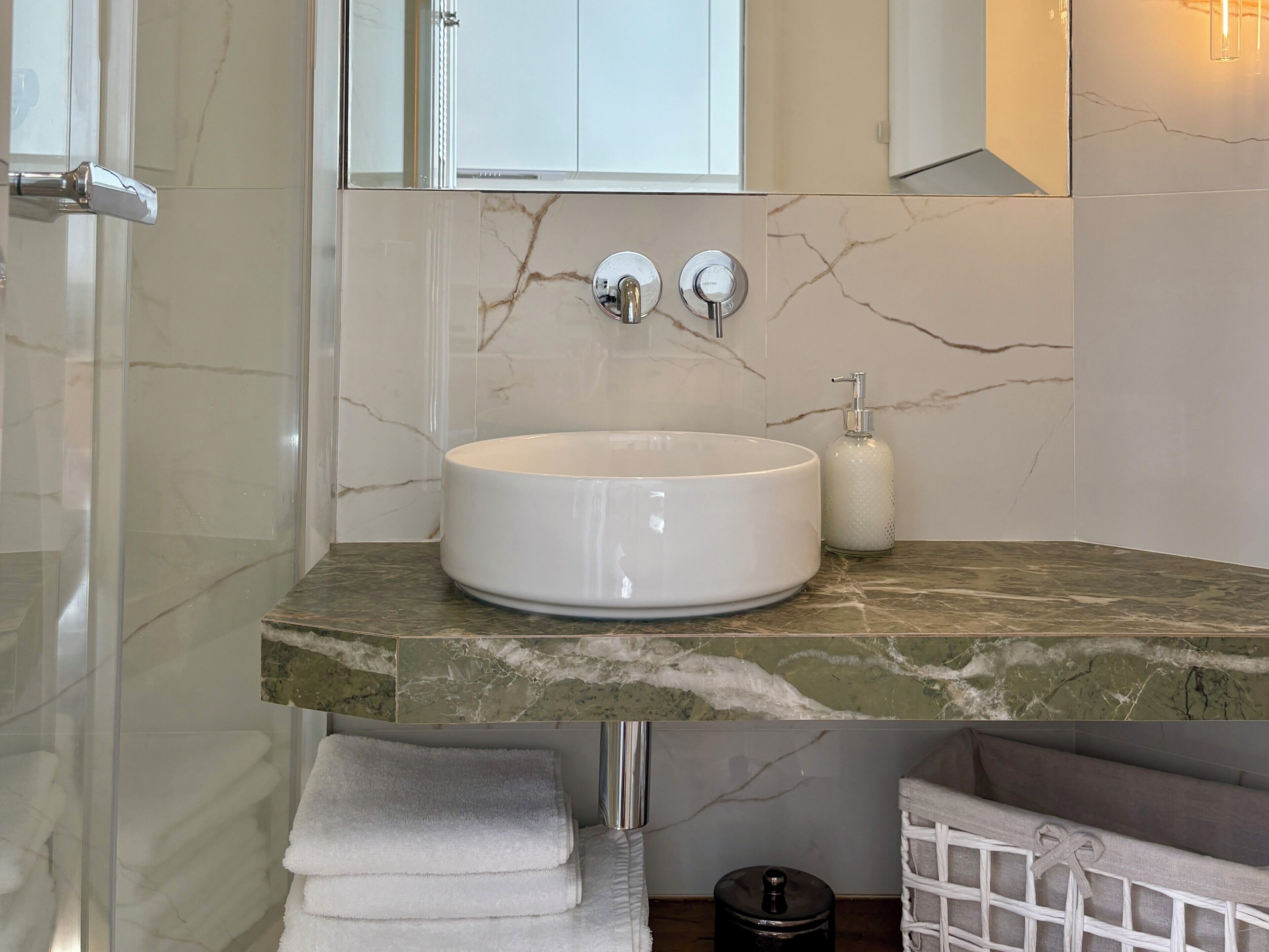 Une salle de bain avec un comptoir en marbre, un lavabo blanc, un distributeur de savon et un porte-serviettes.