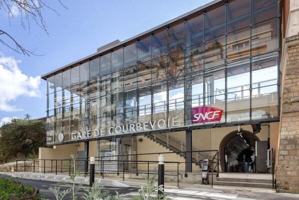 A modern building with large glass windows and a sign reading "GARE DE COURBEVOIE SNCF". - Home Chic Home - Le Cocon de Paris La Défense (La Garenne-Colombes)