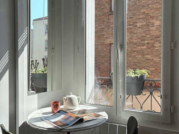 A small round table with a newspaper, a white teapot, and a red mug. - Home Chic Home - Le Cocon de Paris La Défense (La Garenne-Colombes)