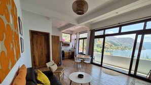 Een moderne woonkamer met een bank, een eethoek en grote ramen met uitzicht op zee.