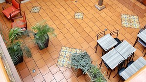 Un patio interior amplio con escaleras de madera, zonas de estar y plantas en macetas.