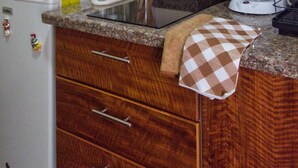 Una cocina con armarios de madera, microondas, cafetera y extractor de acero inoxidable.