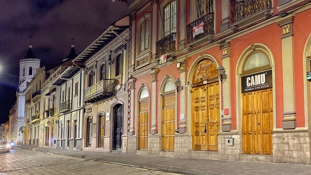 Una calle histórica con arquitectura tradicional, incluyendo balcones ornamentados y puertas de madera.