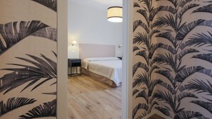 Une pièce comprenant un lit, des tables de chevet, un luminaire suspendu et un plancher en bois.