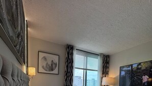 Habitación de hotel con una cama grande, un televisor de pantalla plana montado en la pared y una ventana con cortinas.