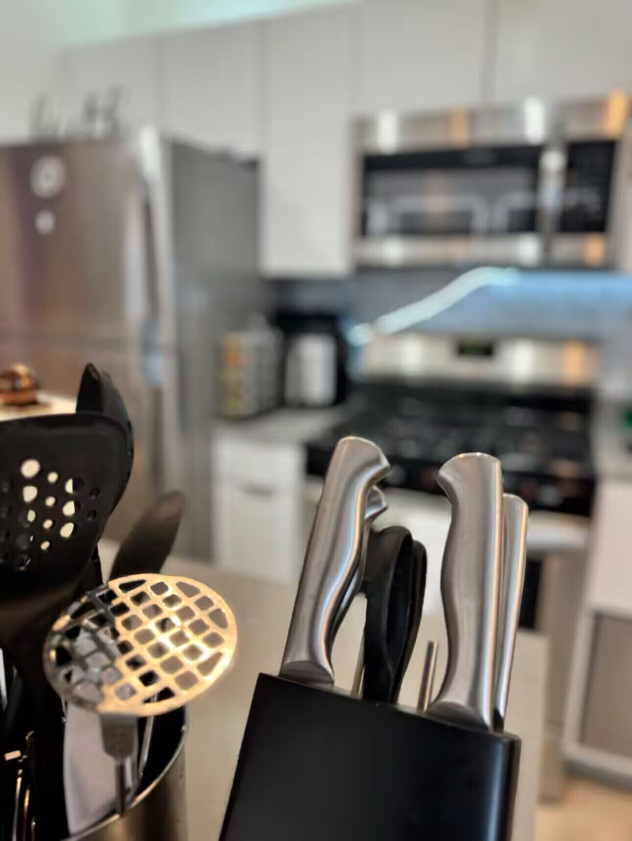 A kitchen with stainless steel appliances, a black knife block, and a colander.