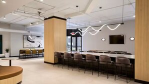 Un restaurant moderne avec un long comptoir, des tabourets de bar et un grand tableau accroché au mur.