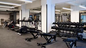 Une salle de sport moderne équipée de divers appareils d’exercice, notamment des tapis de course, des appareils de musculation et un porte-haltères.