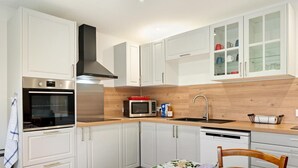 A modern kitchen with white cabinets, stainless steel appliances, and a wooden countertop.