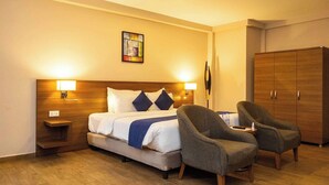 A hotel room with a bed, nightstands, a wardrobe, and two armchairs. - Ah Hotel and Conferences (Accra)