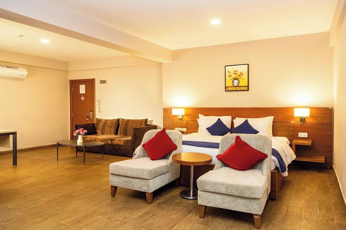 A hotel room with a bed, two armchairs, a small table, and a sofa.