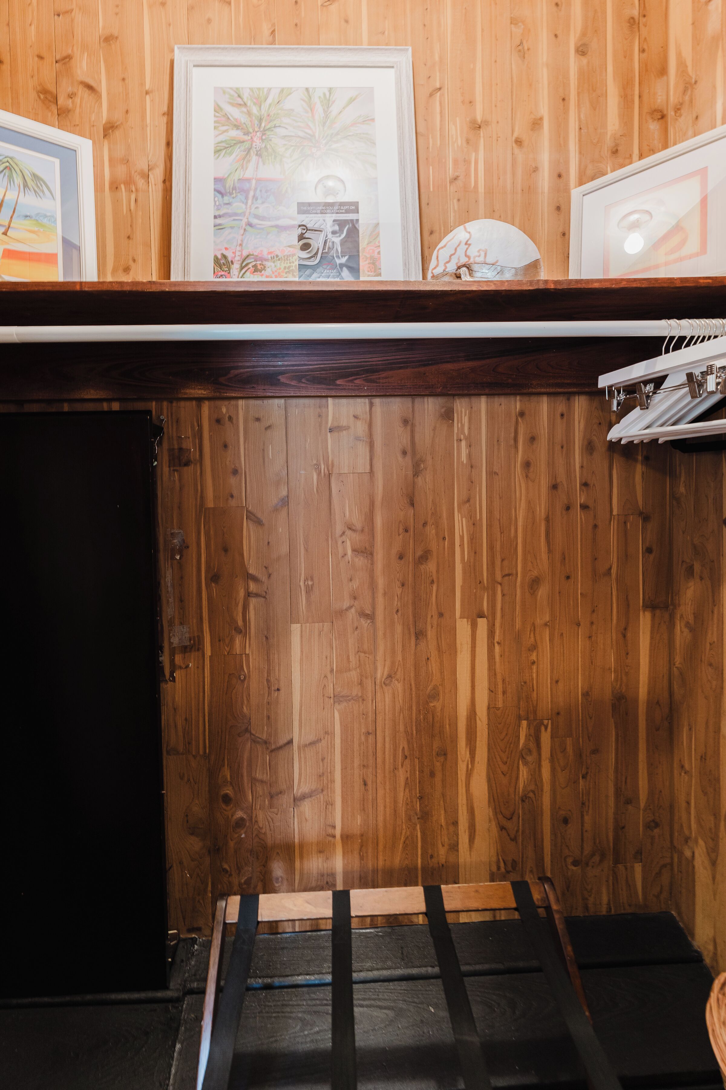 A wooden wall with framed pictures and a shelf.