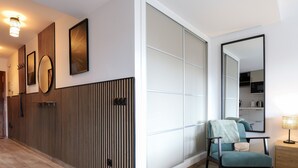 A modern hotel room with a large sliding door, a seating area with a chair and a small table, and a large mirror on the wall.