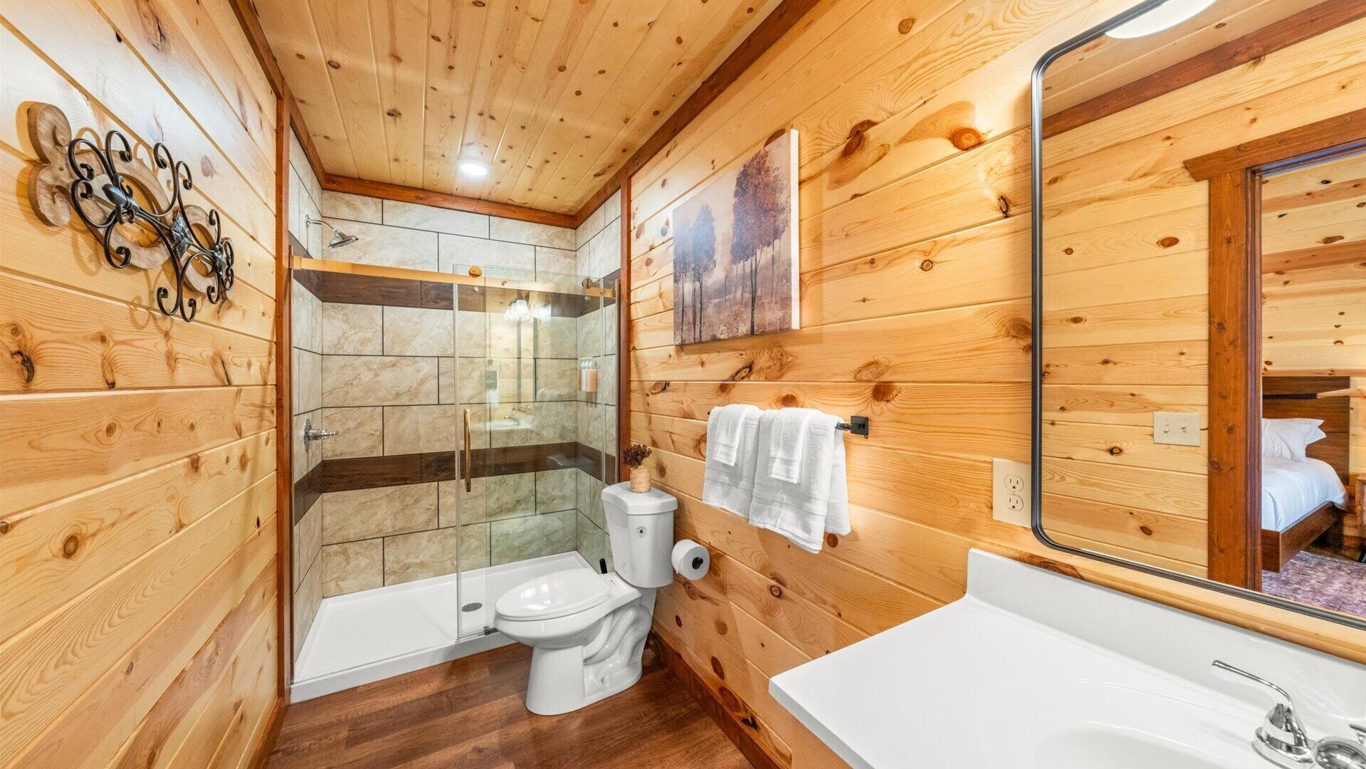 Baño de cabaña de madera con ducha, inodoro y lavamanos.