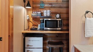 Eine kompakte Küche mit Mikrowelle, Kaffeebereiter und kleinem Kühlschrank.