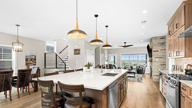A spacious kitchen with a large island, wooden cabinets, and modern pendant lighting.