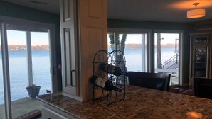 A kitchen with a granite countertop, a wine rack, and a view of a body of water through large windows. - Lake Gage Getaway,
Where every season feels like a vacation. (Angola)