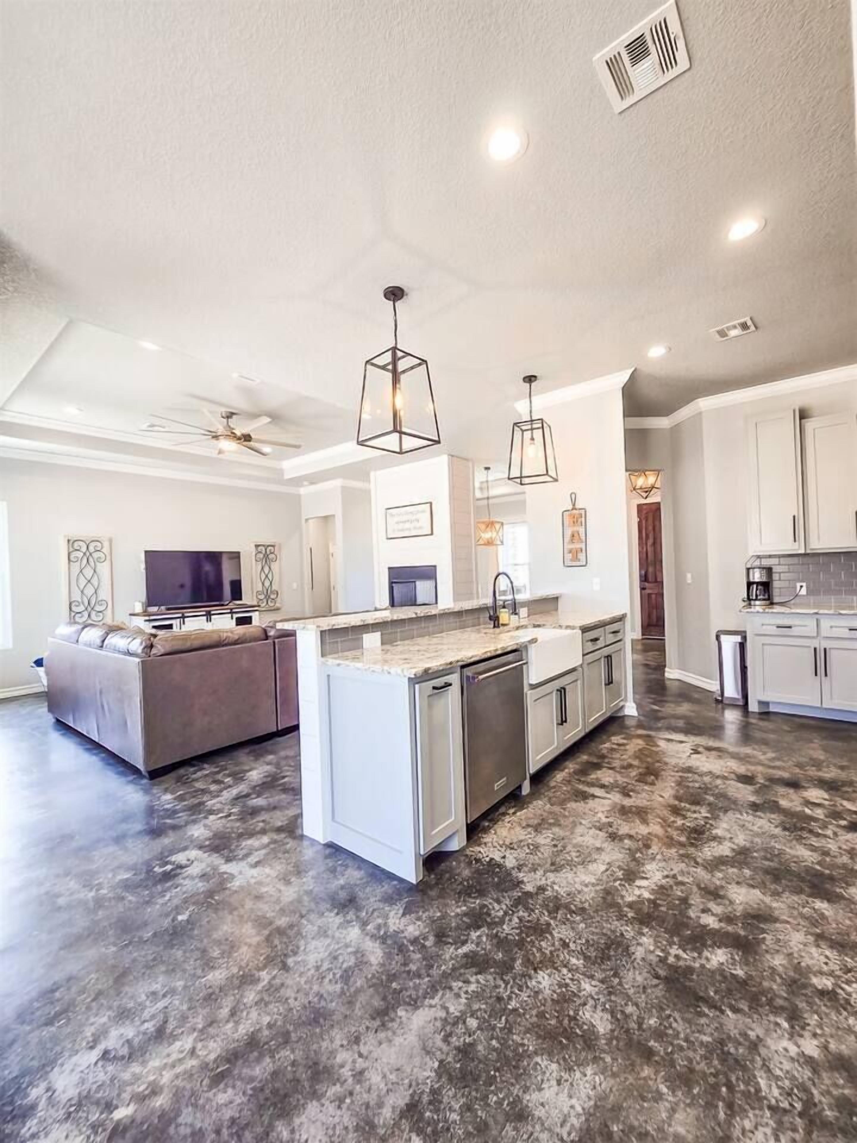 A spacious kitchen with a central island, pendant lighting, and a ceiling fan.