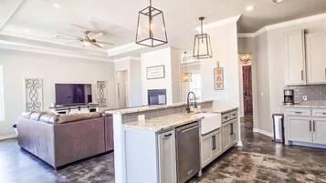 A spacious kitchen with a central island, pendant lighting, and a ceiling fan.