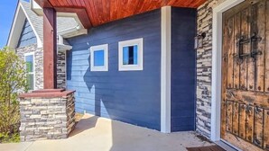 Una casa moderna con base de piedra, fachada azul y puerta de garaje de madera.