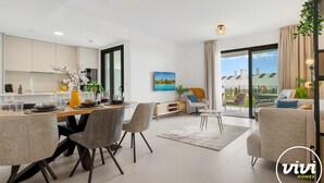 A modern living room with a dining area, a sofa, and a TV. - Julicasa | Garden - pool - terrace (Fuengirola)
