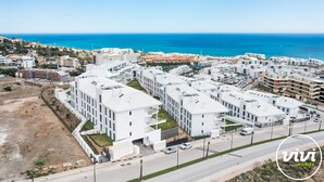 A modern residential area with white buildings, a clear blue sky, and a view of the sea. - Julicasa | Garden - pool - terrace (Fuengirola)