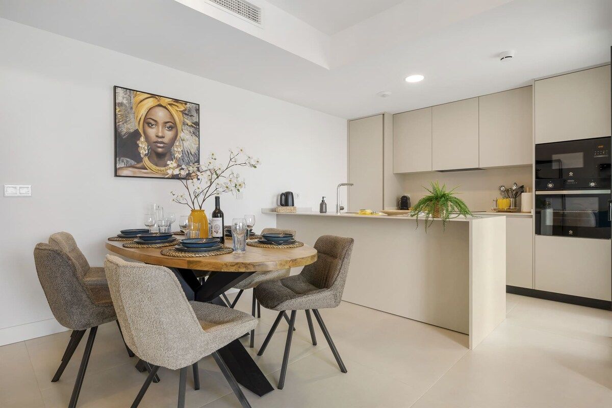 A modern kitchen with a dining area, featuring a round table, chairs, and a kitchen island.