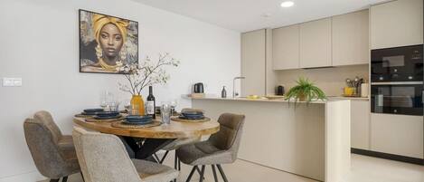 A modern kitchen with a dining area, featuring a round table, chairs, and a kitchen island.