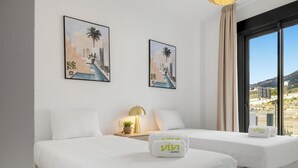 A hotel room with two beds, a nightstand with a lamp, and two framed pictures on the wall. - Julicasa | Garden - pool - terrace (Fuengirola)