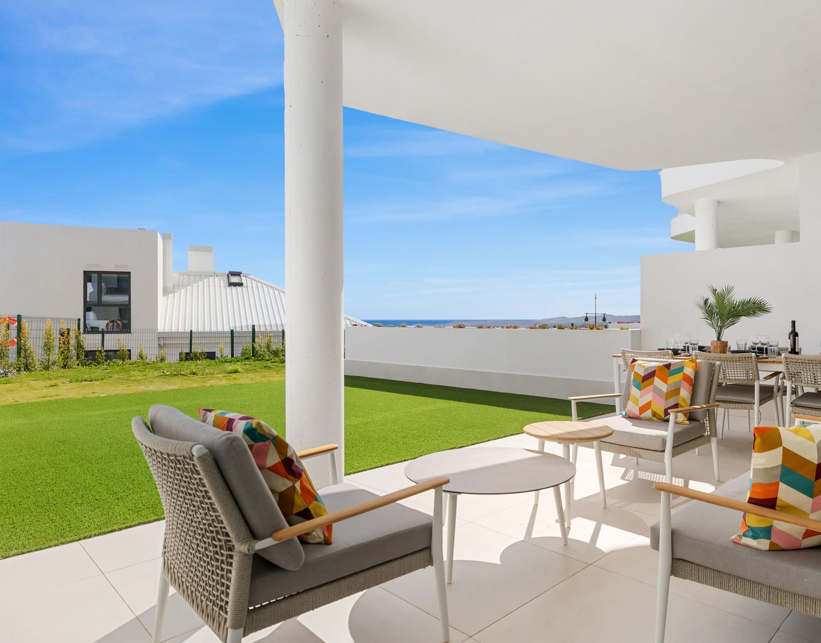 Un patio exterior moderno con mobiliario y vista al mar.