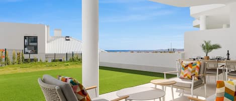 A modern outdoor patio with seating and a view of the sea.