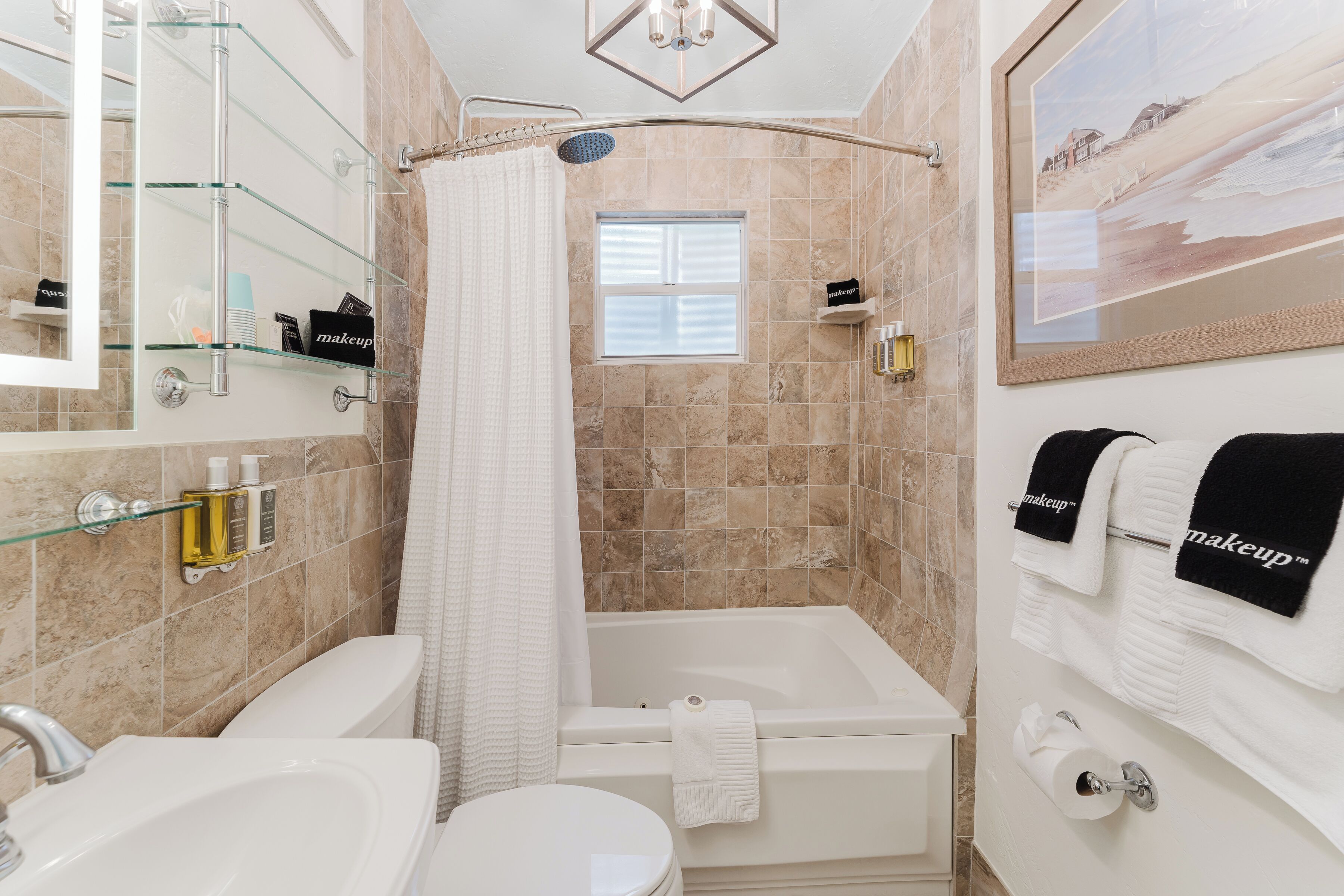 A bathroom with a bathtub, a toilet, a sink, a glass shower enclosure, and a window.