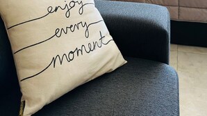 A bedroom with a bed, a headboard, a pillow with the text "enjoy every moment," and a window with a view of trees. - A- Centrally located apartment 9 de Julio I (San Carlos de Bariloche)