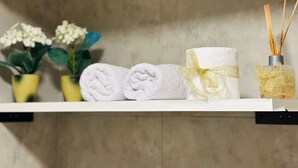 A shelf with neatly folded towels, a decorative item with a gold ribbon, and a reed diffuser. - A- Centrally located apartment 9 de Julio I (San Carlos de Bariloche)