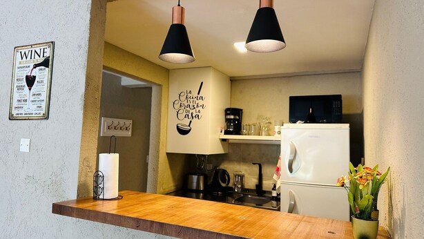A kitchen with a wooden countertop, hanging pendant lights, a refrigerator, and a wall-mounted sign. - A- Centrally located apartment 9 de Julio I (San Carlos de Bariloche)