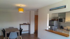 A modern kitchen with a microwave, toaster, and refrigerator. There is a dining area with a table and chairs.