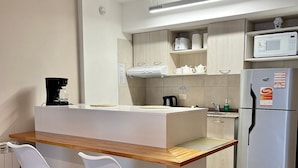 A modern kitchen with a central island, two white chairs, a stainless steel refrigerator, and a microwave. - Exclusive downtown apartment (San Carlos de Bariloche)