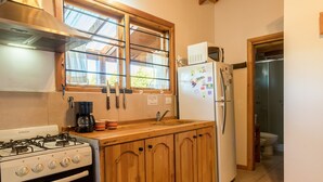 A kitchen with wooden cabinets, a gas stove, a refrigerator, and a window with a view.