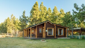 A log cabin with a porch, a covered patio, and a fenced yard.