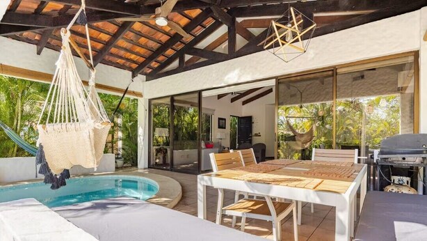 A poolside area with a table and chairs, a hanging hammock, and a barbecue grill. - Casa de Palmas -Modern Villa in 4 Star Beach Resort Short Walk to Playa Hermosa! (Playa Hermosa)